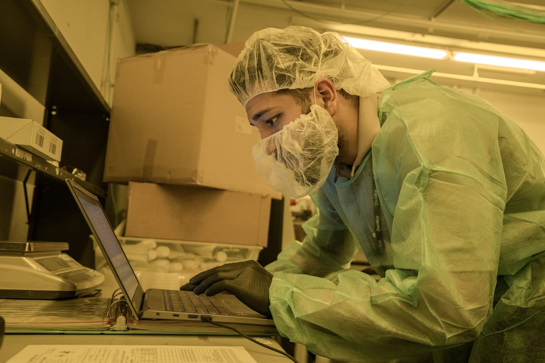 Technician in protective clothing recording service data on a laptop