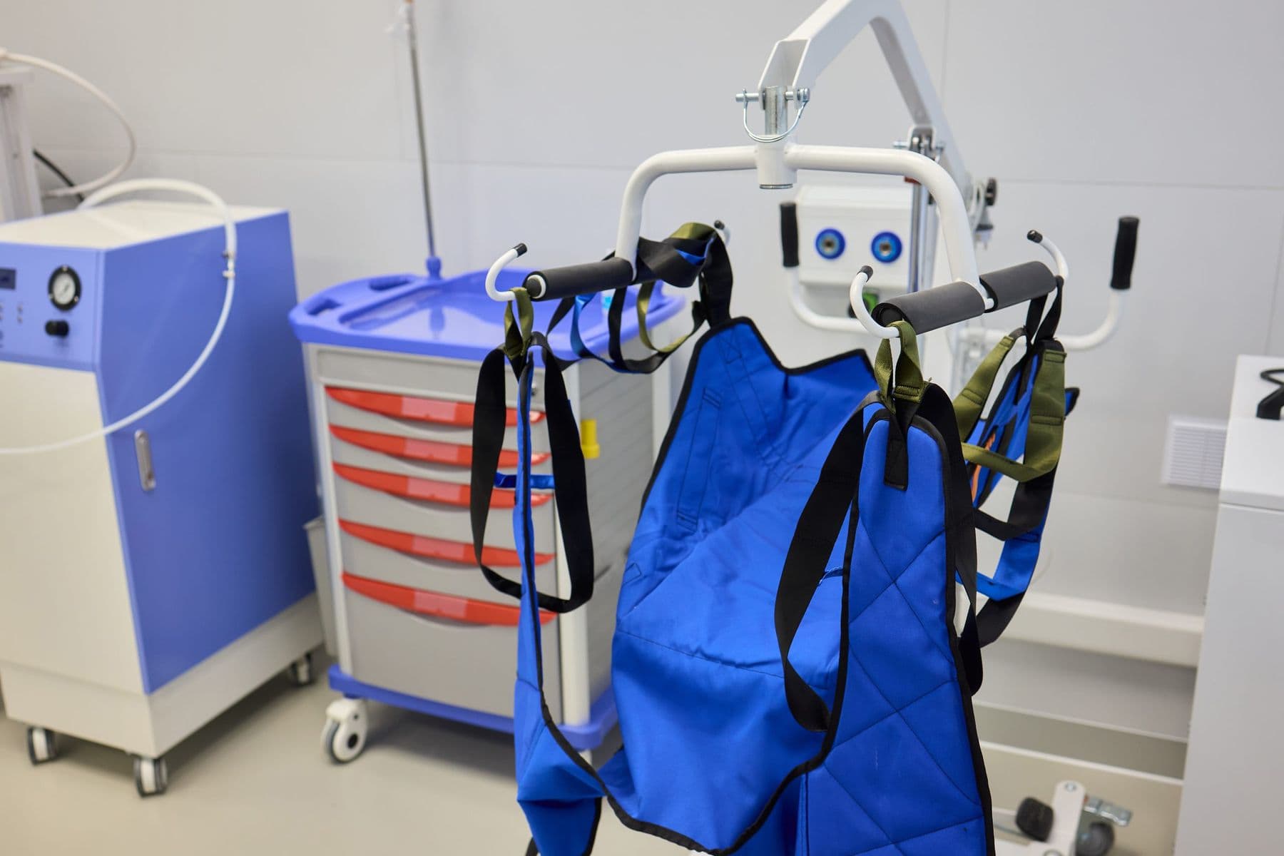 Patient lift with blue sling in a clinical room