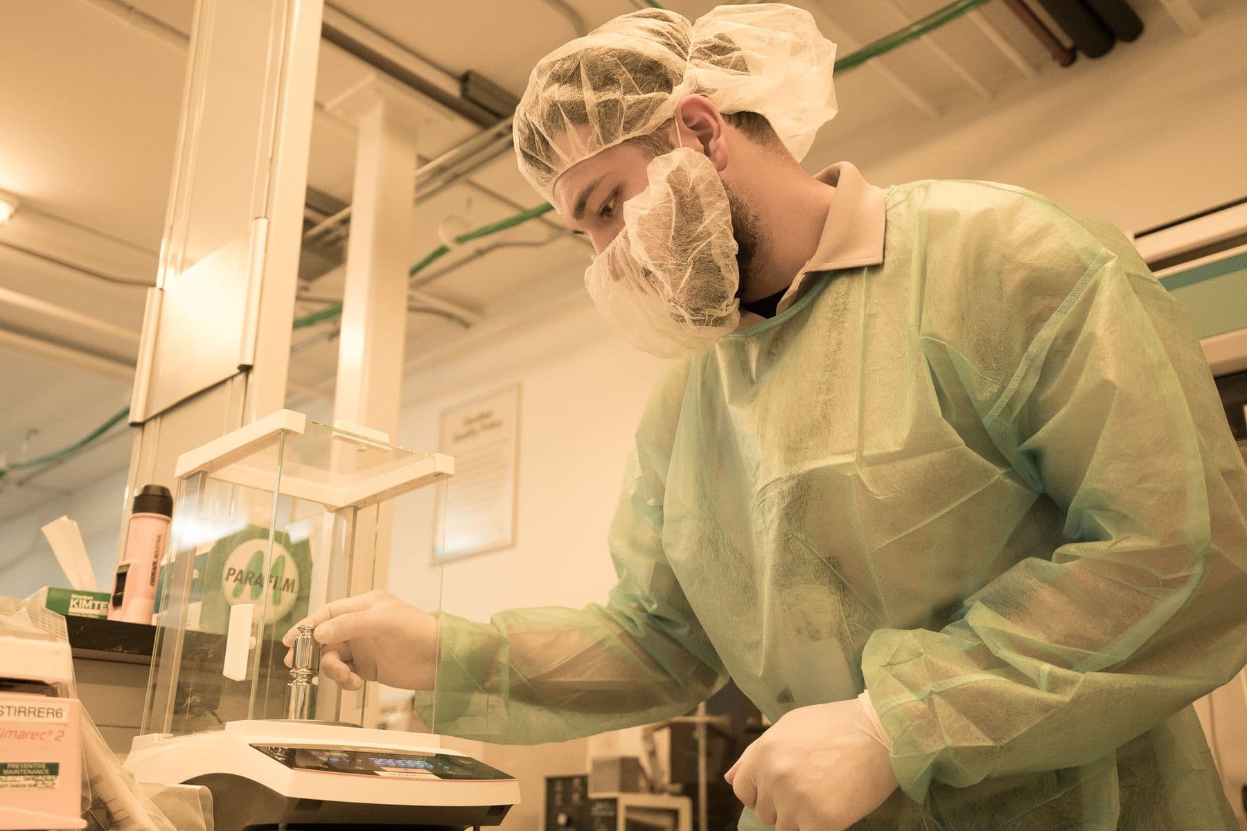 Technician in protective gear testing a laboratory balance